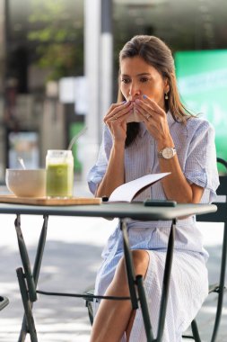 İş kadını peçeteyle ağzını silerken açık hava kahvaltının tadını çıkarıyor, uzaktan çalışıyor.