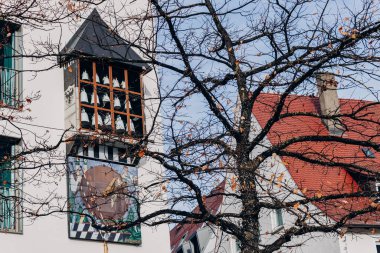 Evin duvarında çanlar olan antika bir saat. Ağacın dallarına bakarak. Ulmer Muenster