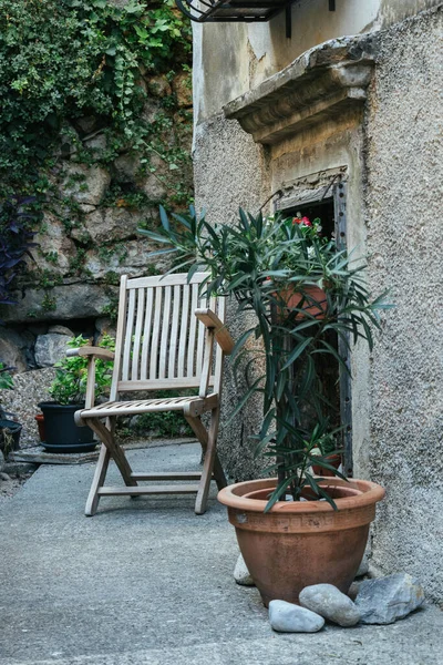 A cozy place to read and relax in a little old courtyard with potted plants and a wooden chair