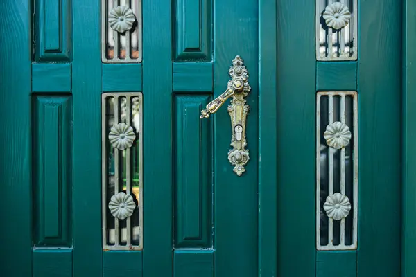 Mysterious closed green doors with wrought iron decorations