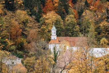 Sonbahar ormanlarının ortasındaki dağ yamacındaki kilisenin manzarası.