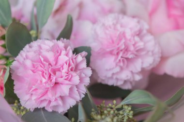 Pastel kağıda sarılmış gül ve karanfillerle süslenmiş yumuşak pembe çiçek buketi.