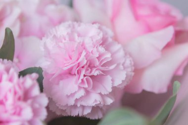 Pastel kağıda sarılmış gül ve karanfillerle süslenmiş yumuşak pembe çiçek buketi.