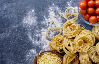 Makarna, peynir ve domatesli mutfak masası.