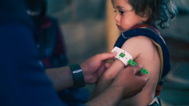 Bir doktor mülteci kampında çocukların yetersiz beslenmesini inceliyor. Yetersiz beslenme orta-üst kol çevresi kemeri kullanılarak ölçüldü.