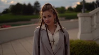 Brunette Girl with dreadlocks pose and look to camera, sunset time, beautiful background . High quality 4k footage