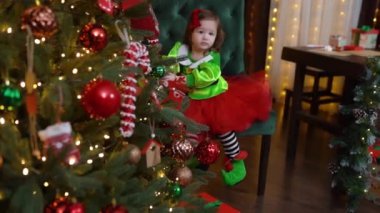 Mariupol, Ukrayna - 12.10.2021: Güzel elbiseli küçük bir kız Noel ağacı süslemesi, yeni yıl görüntüleri. Yüksek kaliteli FullHD görüntüler