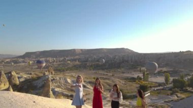 Girls in different dress in Cappadocia with champagne, Sunset view, Hot air Balloons, Drone footage. High quality FullHD footage