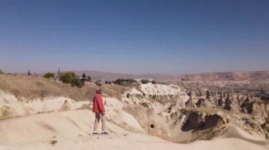 Türkiye, Kapadokya, 10.08.2021: Kapadokya kayalarında kırmızı gözlüklü ve şapka giyen bir adam, Yüksek kalite FullHD insansız hava aracı görüntüleri