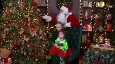 Mariupol, Ukrayna - 12.10.2021: Bir anne küçük kızıyla Noel Baba 'ya bakar ve Noel ağacına dokunur. Yüksek kaliteli FullHD görüntüler