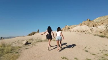 Turkey, Cappadocia, 10.08.2021: Back view of Two girls running in Cappadocia, drone footage. High quality FullHD footage