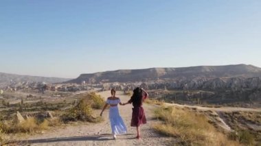Türkiye, Kapadokya, 10.08.2021: Kapadokya, Türkiye Vadisi 'nde yürüyen iki kız, Drone görüntüsü, Sunset. Yüksek kaliteli FullHD görüntüler