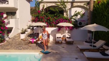 Beyaz bikinili kadının hava manzarası, Türkiye 'nin Oludeniz kentindeki otelde havuzda yüzmeye gidiyor. Yüksek kaliteli İHA FullHD görüntüleri