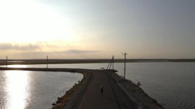 Aerial drone view young woman running on a beach on road, sunset time, fitness, sport, drone footage. High quality FullHD footage