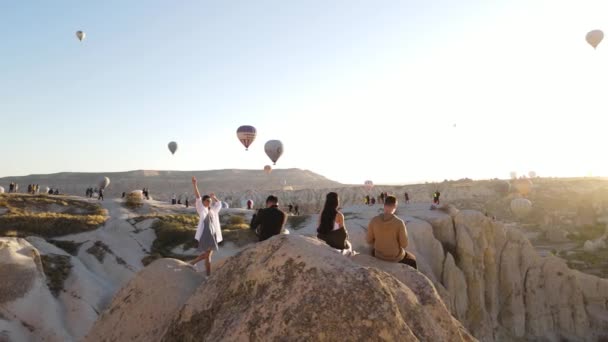トルコ カッパドキア 2021 カッパドキアの写真撮影モデル 岩の上に座っている人々 ドローンパノラマビュー 熱気球 高品質のフルHd映像 — ストック動画
