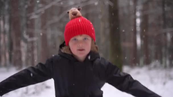 Kırmızı Şapkalı Küçük Çocuk Atlayan Kız Kameraya Gülümsüyor Kış Ormanı — Stok video