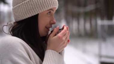 Close up footage of girl, drinking hot drink, smile, forest, winter season, snow background . High quality 4k footage