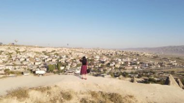 Cappadocia kayalıklarında kırmızı elbiseli bir kızın panoramik görüntüsü, İHA görüntüleri. Yüksek kaliteli FullHD görüntüler