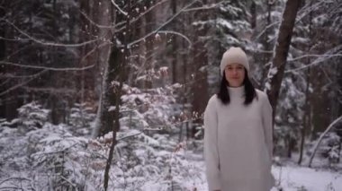Girl is walking in white clothes and look at the camera, winter season in forest Austria, 4k video. High quality 4k footage