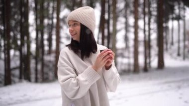 Cute girl drink hot coffee and smiling, winter forest, snow day, 4k video. High quality 4k footage