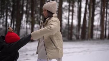 Avusturya 'daki kar ormanlarında dönen ve oynayan küçük çocuklu tatlı bir kız, 4K görüntü. Yüksek kalite 4k görüntü