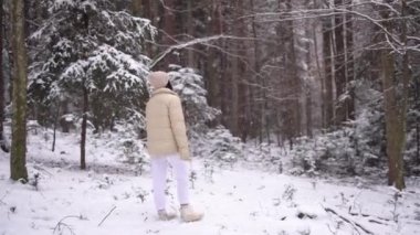 Girl in jacket and hat is walking in snow forest, winter season, 4k video. High quality 4k footage