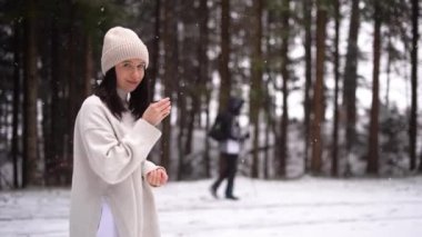Girl stay in winter background forest, and drink hot tea, people walk away in background. High quality 4k footage