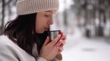 Kızın yakın çekimleri, sıcak kahve içmesi, gülümsemesi, ormanı, kış mevsimini, kar geçmişini. Yüksek kalite 4k görüntü