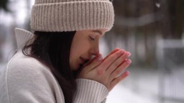 Close up footage of girl, warm her hands, smile, forest, winter season, snow background . High quality 4k footage