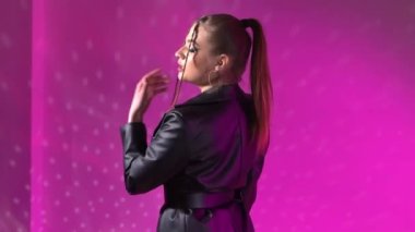Side view portrait purple neon girl at the studio on photo shoot. Slow-motion. High quality FullHD footage