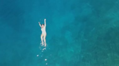 Girl in a white swimsuit swims in the sea. Aerial view. High quality FullHD footage
