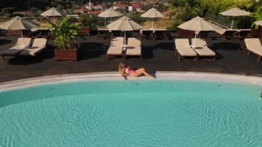 The girl is relaxing on pool in swimsuit. High quality FullHD footage