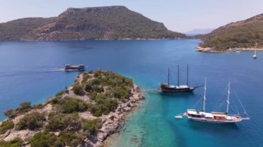 Turkish Oludeniz Beach. Turkey. Yachts , Catamarans and Boats sailing in crystal clear blue water of ocean, with mountain cliffs in the background. High quality FullHD footage