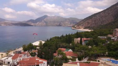 Paraşütçünün Oludeniz 'deki otele inişi. Kırmızı paraşüt. Hava atışı. Yüksek kalite 4k görüntü
