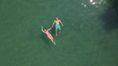 A man and a woman swim on their backs. Transparent beautiful sea. Drone video. High quality 4k footage