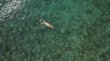 Woman in white swimsuit swims on her back in the mediterranean sea. High quality 4k footage