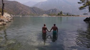 A man and a girl go into the water on the shore of the blue lagoon. High quality 4k footage