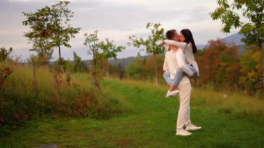 Happy man holding carrying spinning woman having fun enjoy in nature, sunset. High quality 4k footage