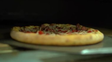 Taking the pizza out of the fired oven. The pizza is cooked in the oven. Chef with blue gloves taking pizza out with a shovel into the fired oven. High quality FullHD footage