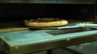 Chef with blue gloves taking pizza out with a shovel into the fired oven. Baked meal. High quality FullHD footage