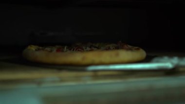Ready pizza taking out with a shovel into the fired oven. Baked meal. High quality FullHD footage