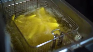 French fries in the deep fryer, in a fast food restaurant, crispy fries, Junk food concept, top view Close up. High quality FullHD footage