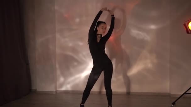 黒とチョーカーのセクシーな女の子はスタジオでオレンジ色のネオンの背景で踊っています スローモーション 高品質のフルHd映像 — ストック動画