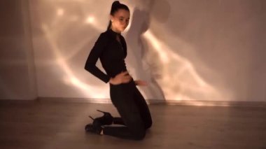 Yüksek topuklu ayakkabılı, yerde dans eden zayıf genç bir kadın stüdyodaki performans sırasında ağır çekimde. Yüksek kaliteli FullHD görüntüler