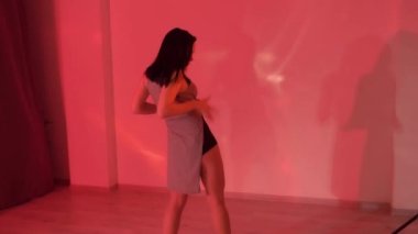 Baştan çıkarıcı elbiseli, siyah topuklu ayakkabılı seksi esmer kız ışıklı stüdyoda yerde dans ediyor. Yüksek kaliteli FullHD görüntüler