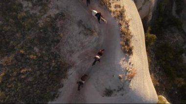 Kapadokya 'da at süren insanların panoramik görüntüsü. Panoramik günbatımı manzarası. Yüksek kalite FullHD insansız hava aracı görüntüleri