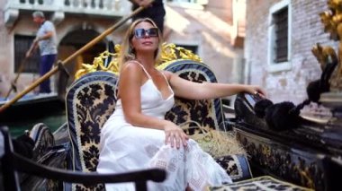İtalya Venedik Kanalı 'nda bir gondolda oturan beyaz elbiseli muhteşem kadın. Yüksek kalite 4k görüntü
