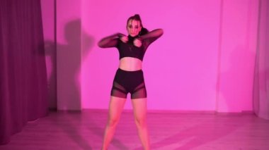 Siyah bluzlu ve transparan kısa taytlı seksi kadın kırmızı ışıklı odada yerde dans ediyor. Yüksek kaliteli FullHD görüntüler