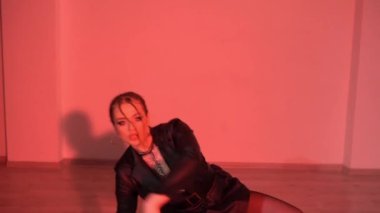 Yüksek topuklu ve deri elbiseli seksi kadın renkli ışıklı odada yerde dans ediyor. Yüksek kaliteli FullHD görüntüler