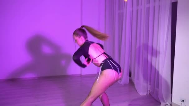 透明なレギンスと作物のトップダンスの魅惑的な女の子は 照明付きの部屋で床の上で踊っています 高品質のフルHd映像 — ストック動画